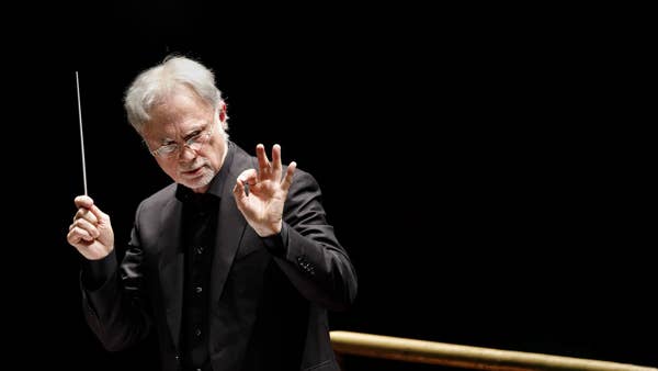 Close up of male conductor in a suit raising his hands.