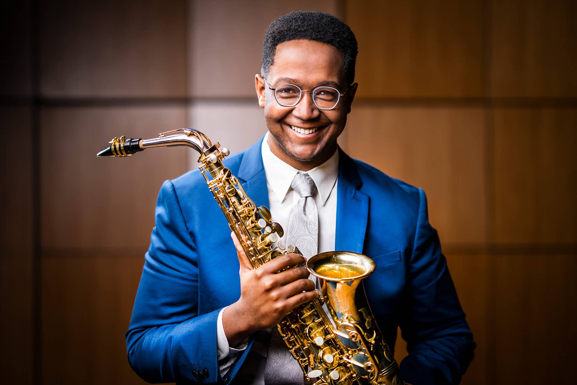 Steven Banks in a blue jacket, holding a saxophone