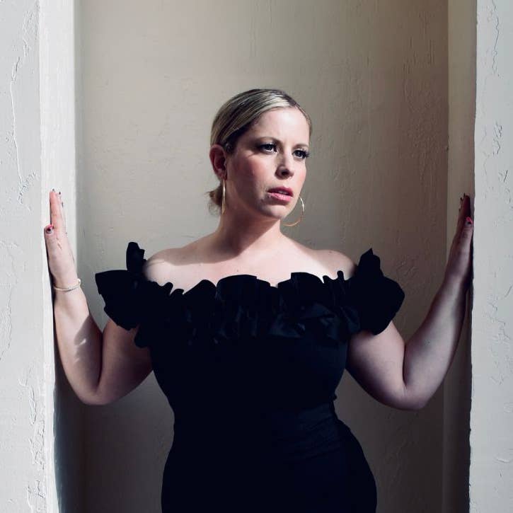 Robyn Black in a black dress posing in an alcove