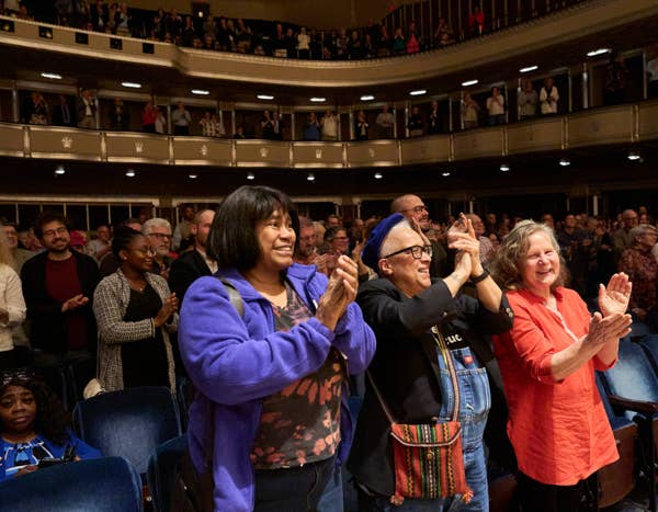 happy audience members standing and clapping in Mandel Concert Hall