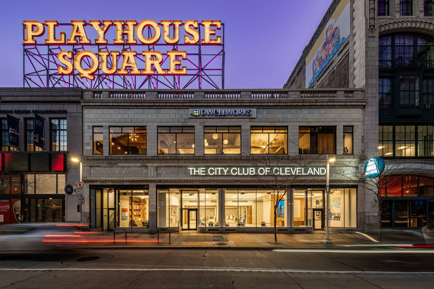 Neon marquee reads Playhouse Square above storefronts for The City Club of Cleveland at dusk.