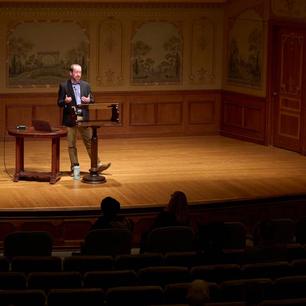 a man in a blue jacket stands on a small stage behind a podium