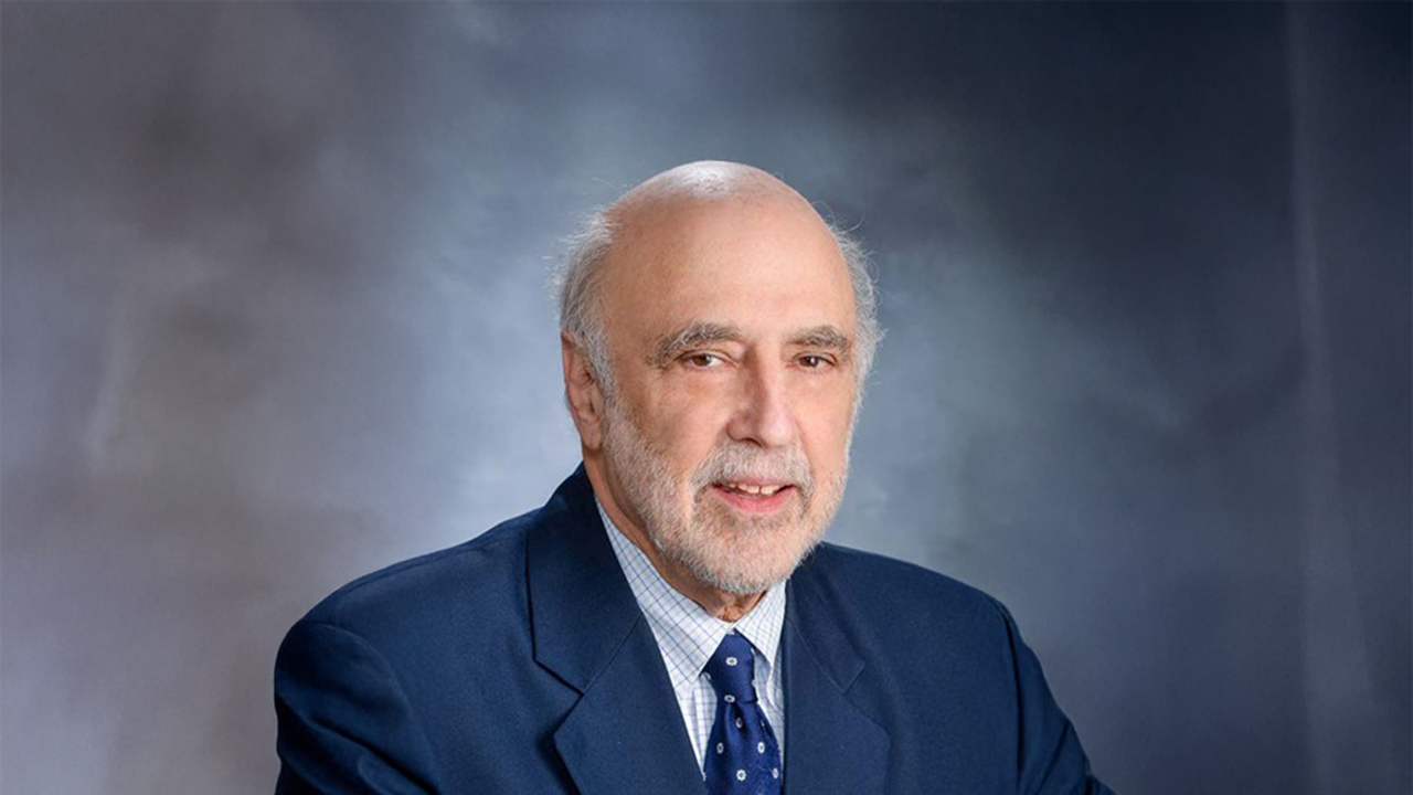 a man in a blue jacket poses for a headshot