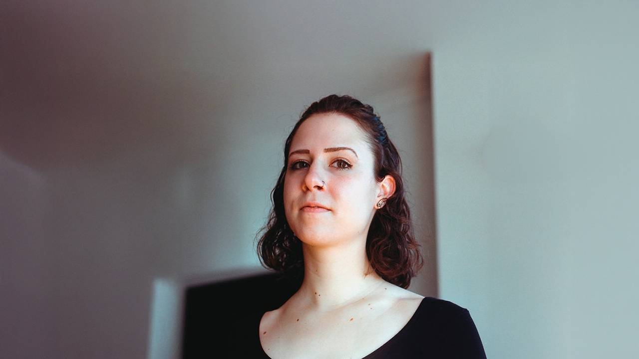 A woman in a black shirt looks into the camera