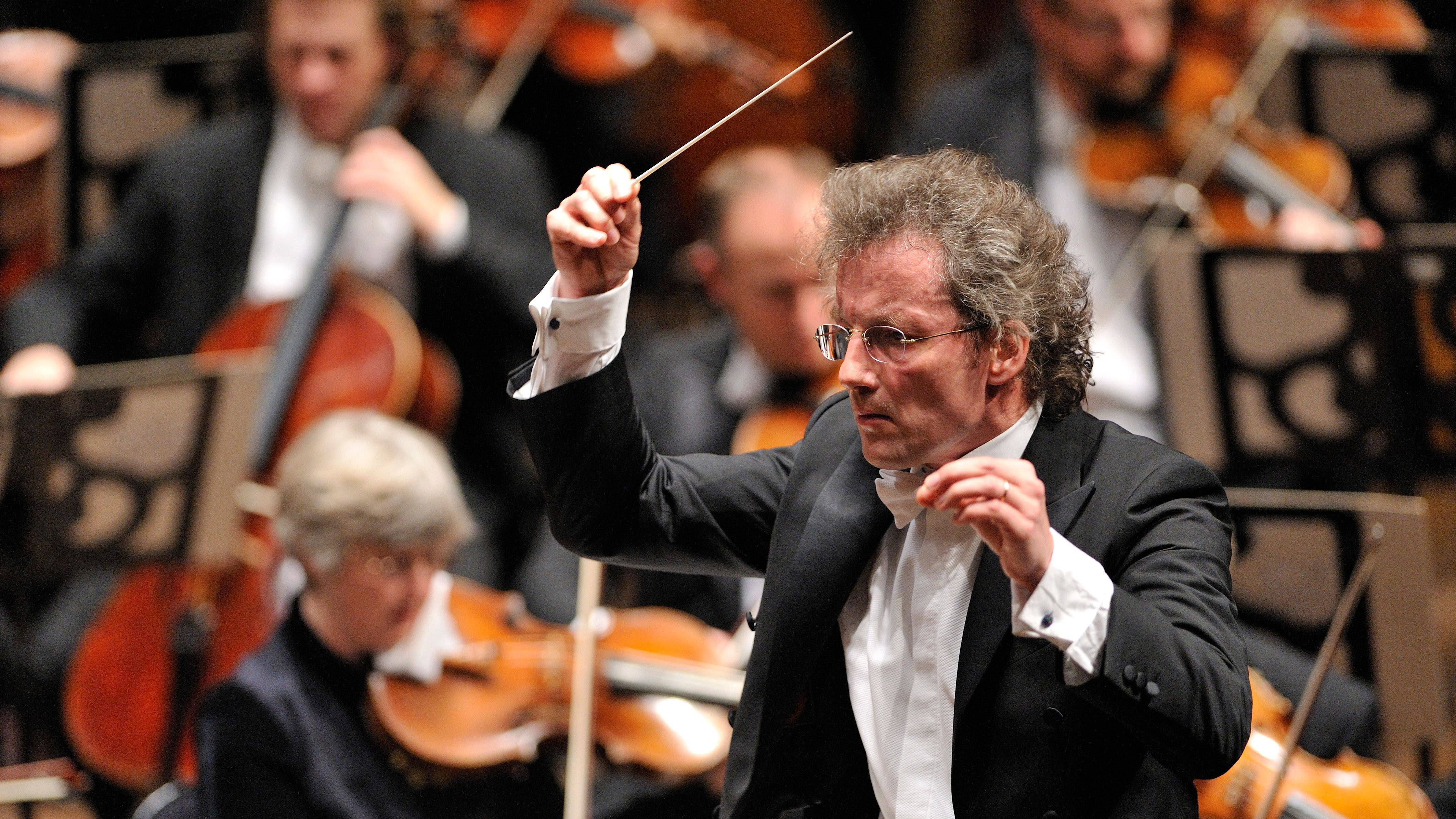 Franz is conducting the Orchestra with a serious expression on his face.