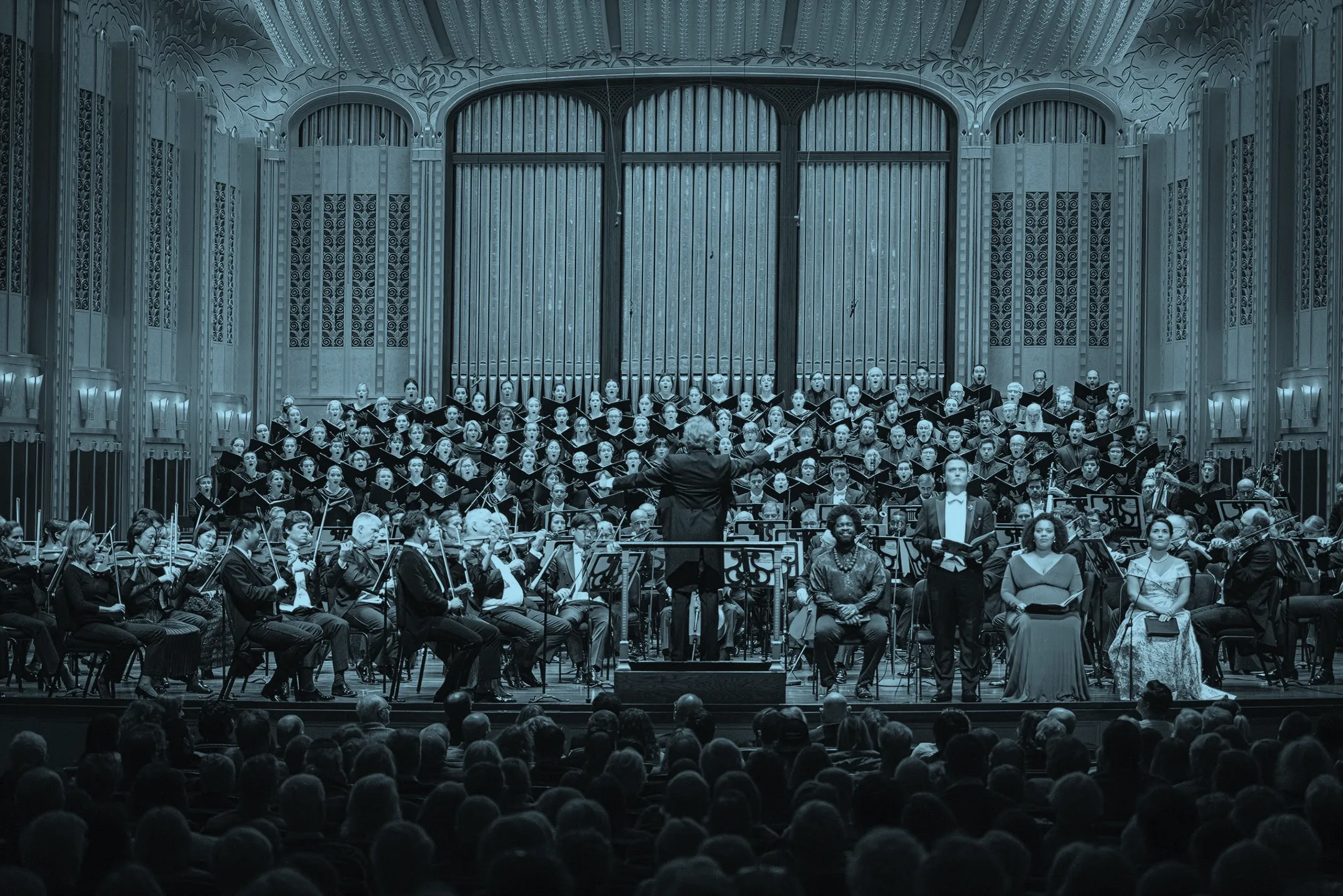 The Cleveland Orchestra and TCO Chorus performing on stage with Franz Welser-Möst leading, surrounded by an ornate interior of MAndelo Concert Hall.