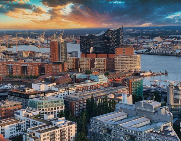 Aerial view of a cityscape with modern buildings, a river, and a dramatic sunset sky with clouds and vibrant colors. Published on December 31, 2020