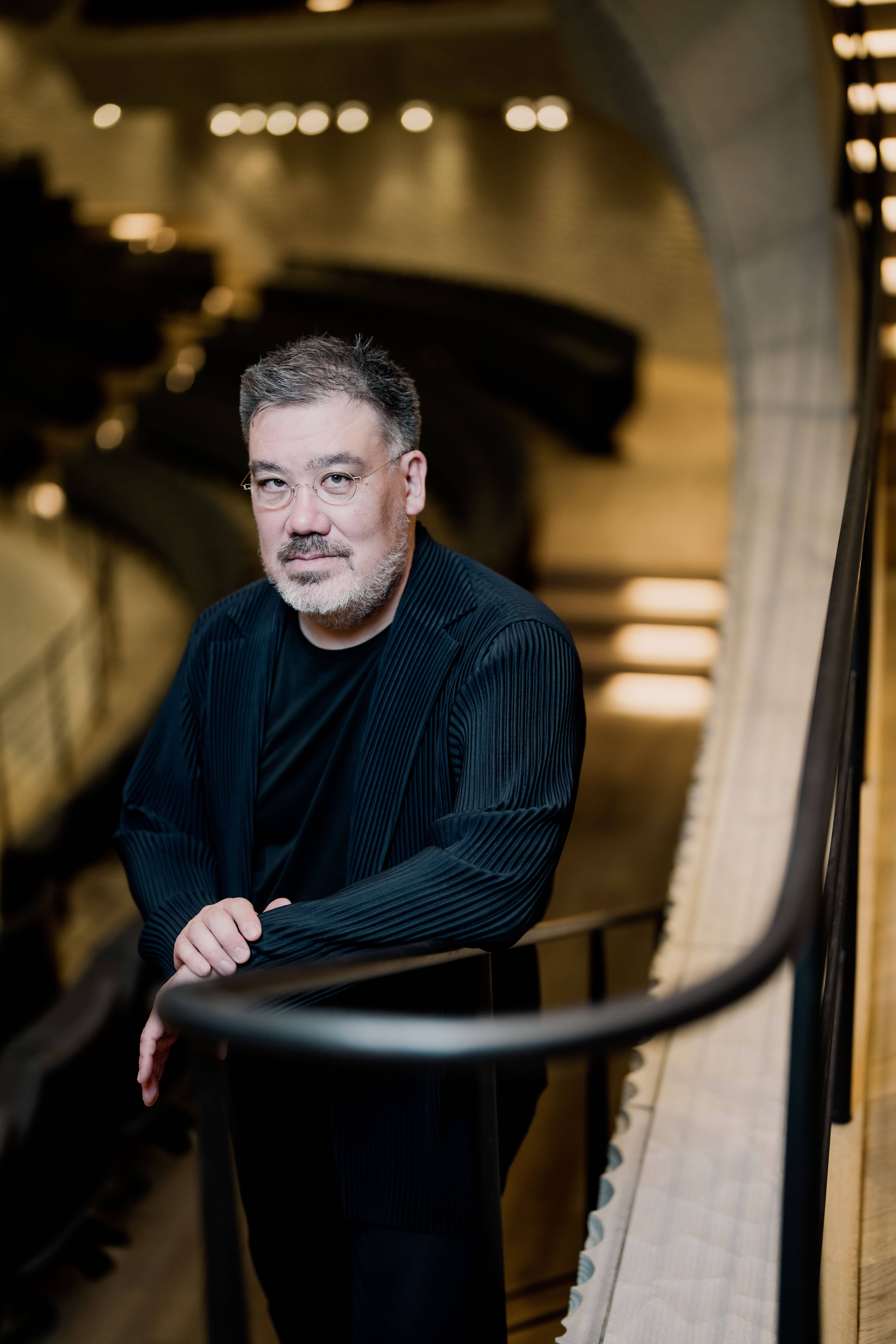 Alan Gilbert posing in a concert hall 