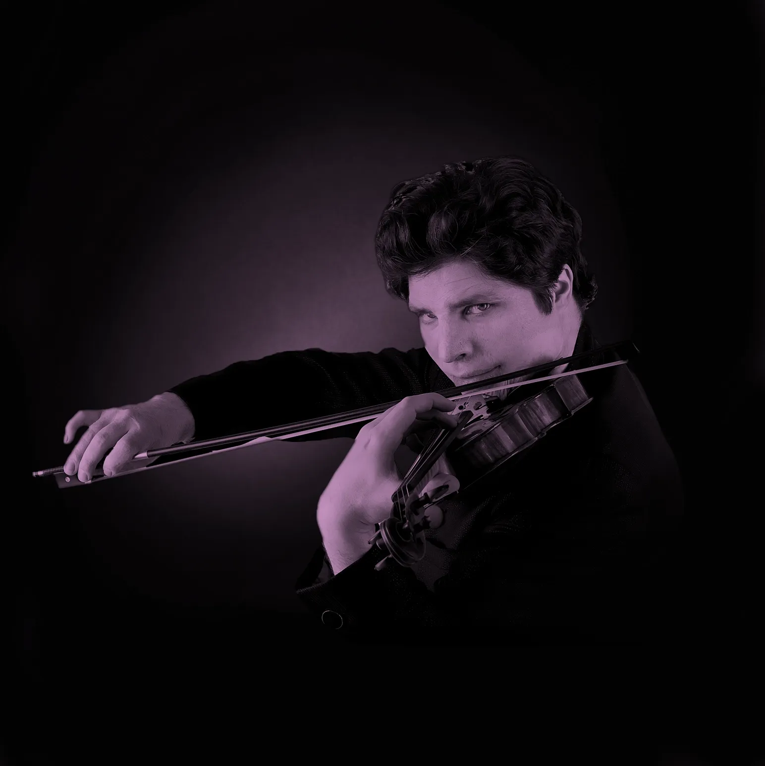 Augustin Hadelich playing a violin with intense focus, set against a dark background.