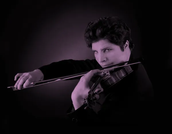 Augustin Hadelich playing a violin with intense focus, set against a dark background.