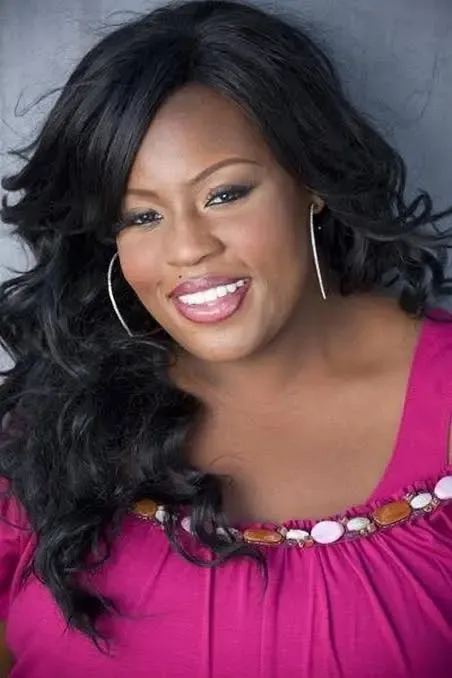 LaKisha Jones, smiling with long black curls, hoop earrings, and a purple top