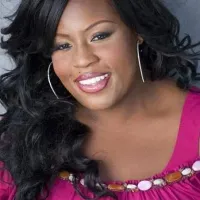LaKisha Jones, smiling with long black curls, hoop earrings, and a purple top