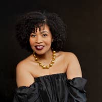 Golda Schultz posing for headshot in a black dress and gold necklace