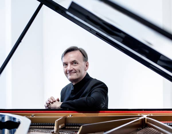 Stephen Hough sits at piano, smiling