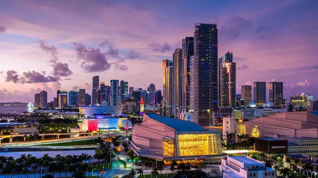 The Adrienne Arsht Center exterior illuminated in the evening, with a city skyline in the background