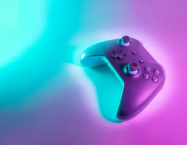 Purple and teal game controller with glowing buttons against a colorful neon gradient background
