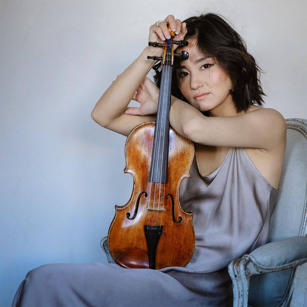 Sayaka Shoji holding a violin, seated in a relaxed pose