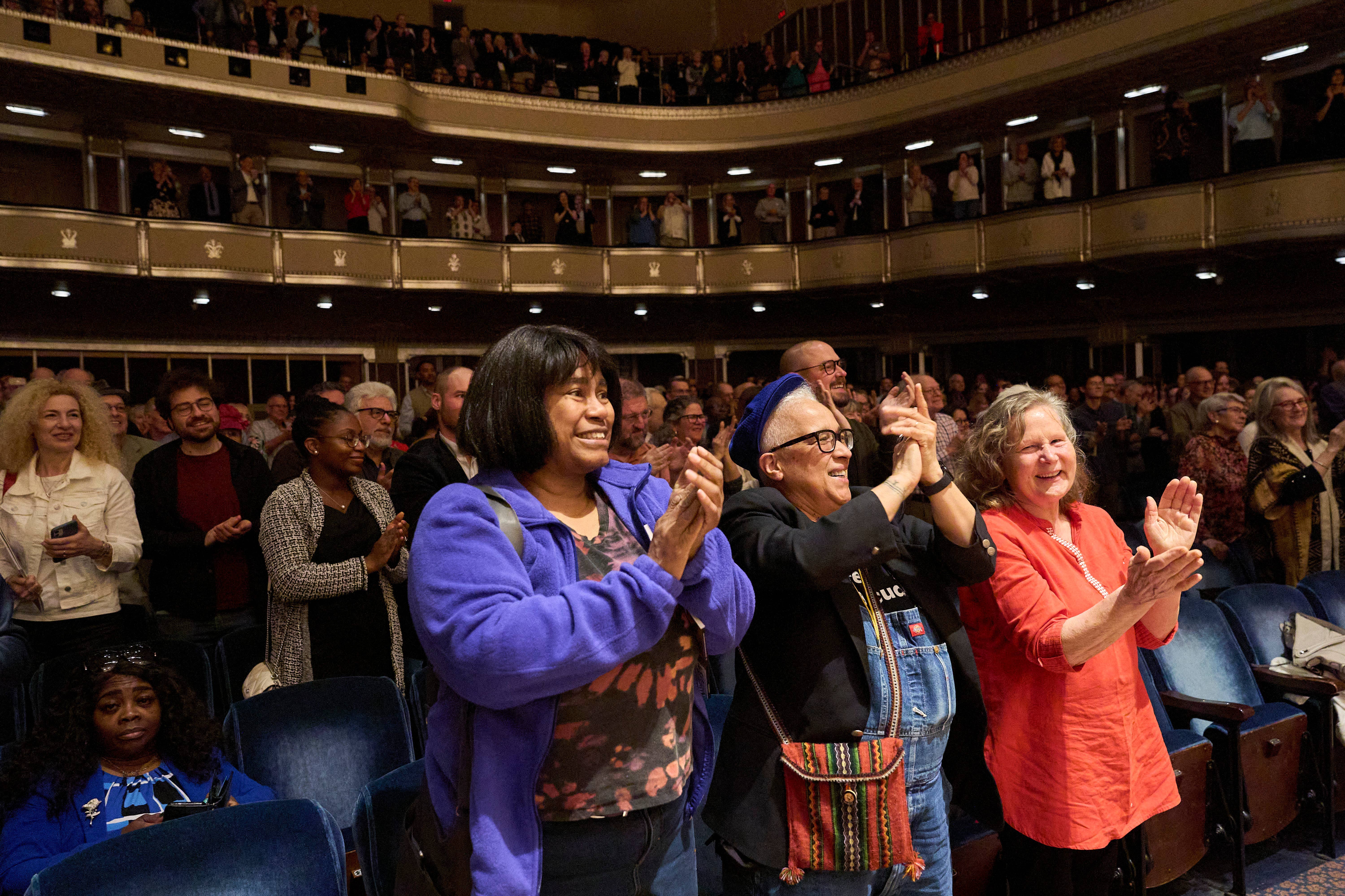 happy audience members standing and clapping in Mandel Concert Hall