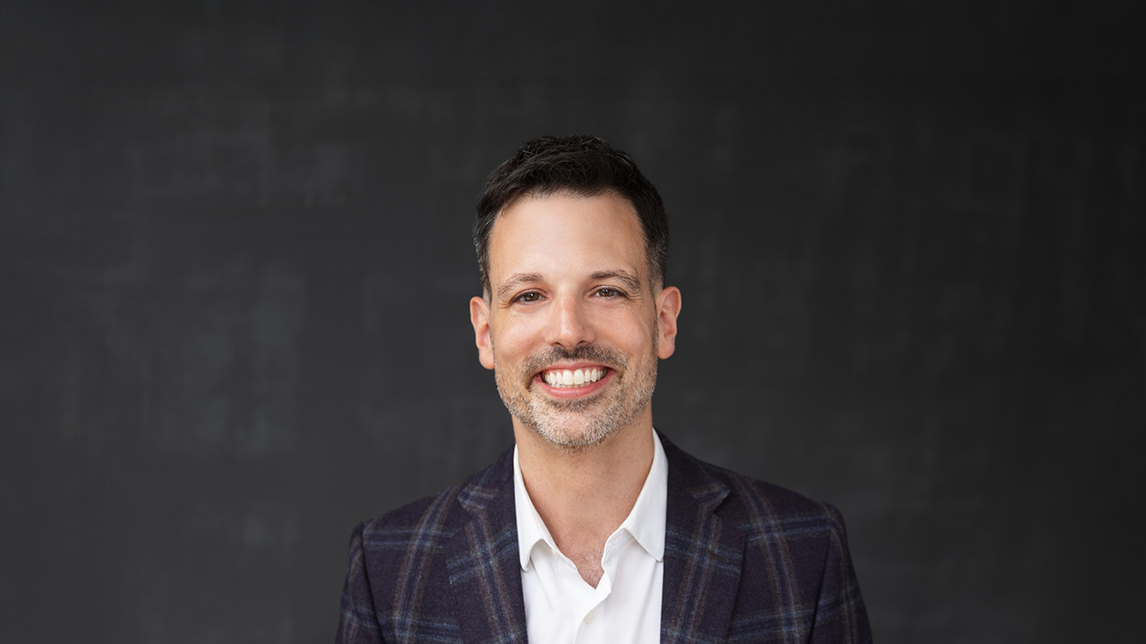 a man in a plaid jacket smiles for a headshop