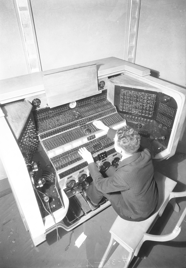 A man sits at an organ console