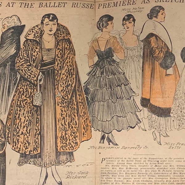 A newspaper depicts women in lavish black and orange coats.