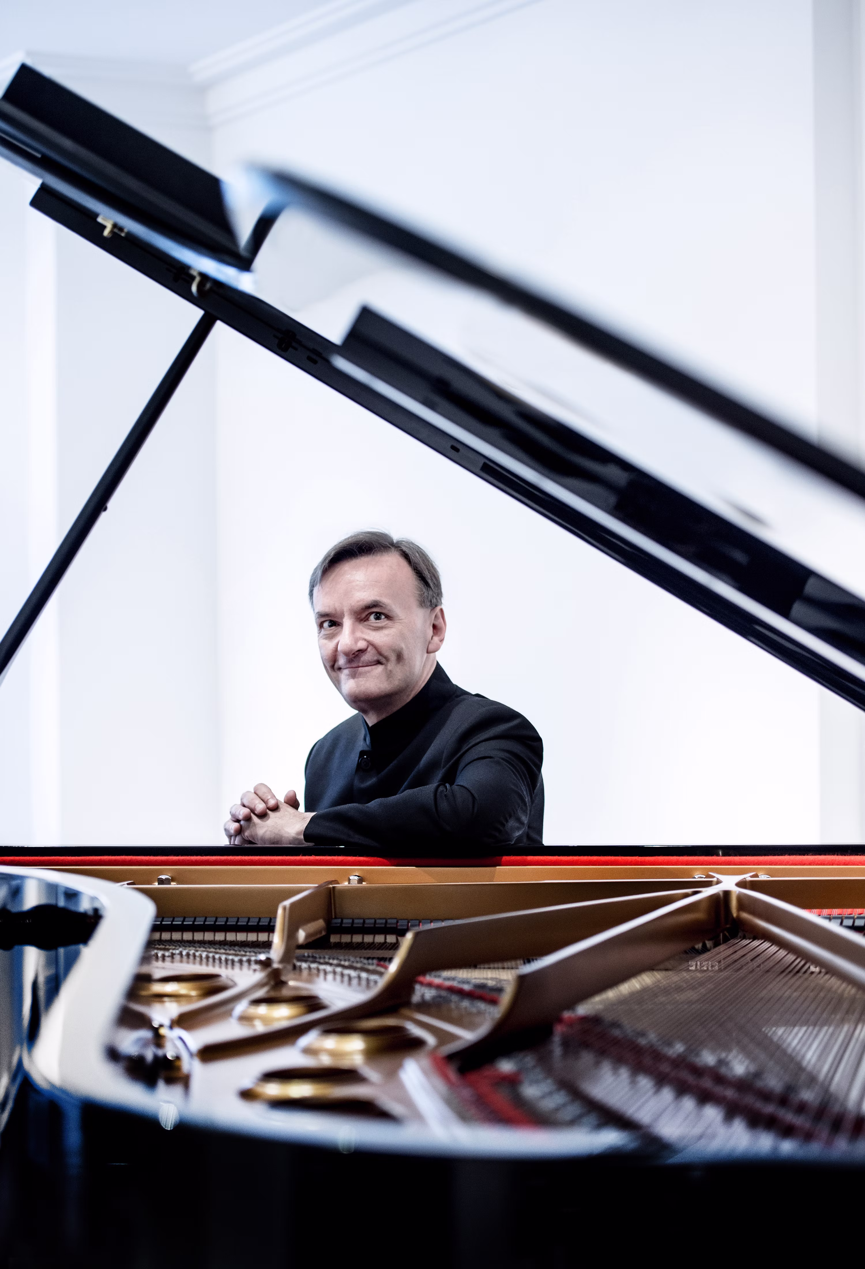 Stephen Hough sits at piano, smiling