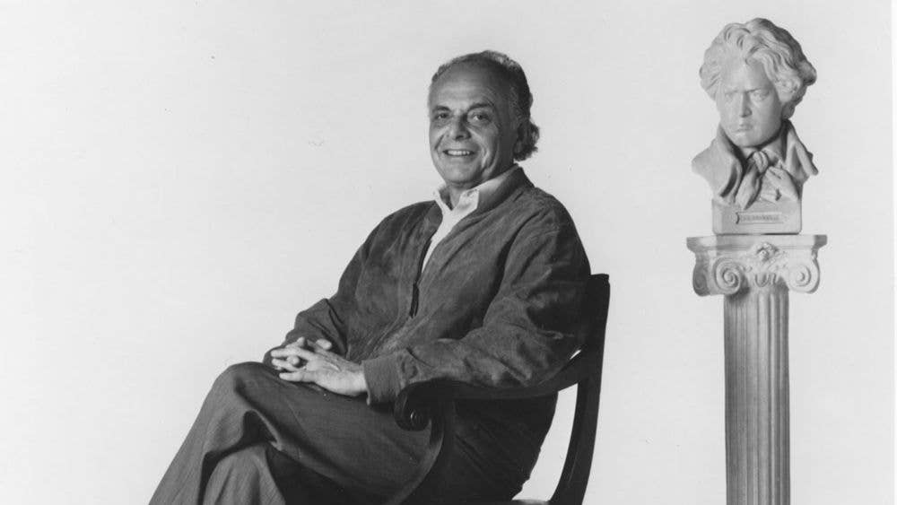 Maazel is seated and smiling at the camera while behind him, to the left, is a bust of Beethoven.