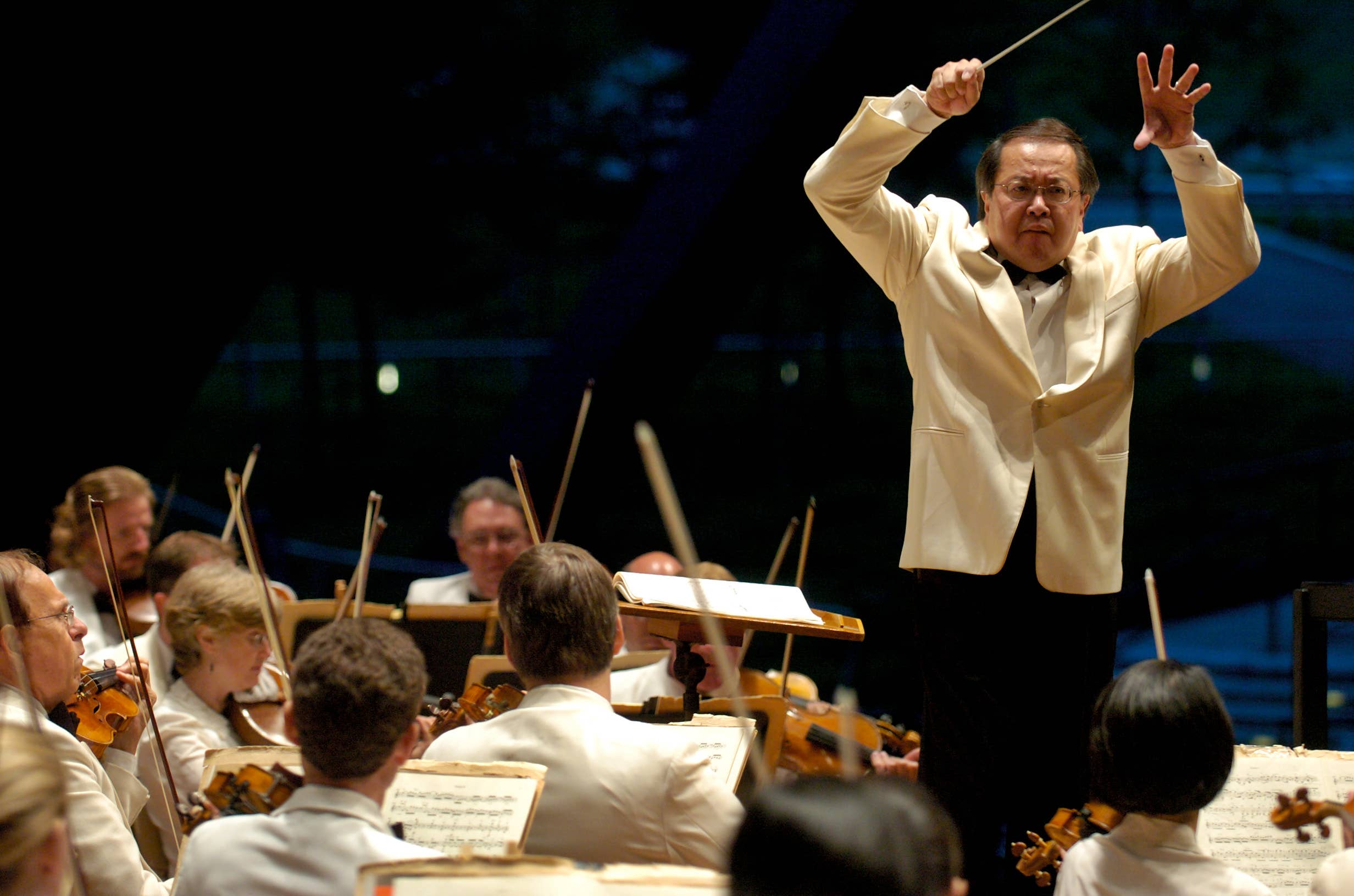 His hands held high, Jahja Ling conducts the Orchestra at Blossom. All are dressed in white jackets: formal dress for Blossom.