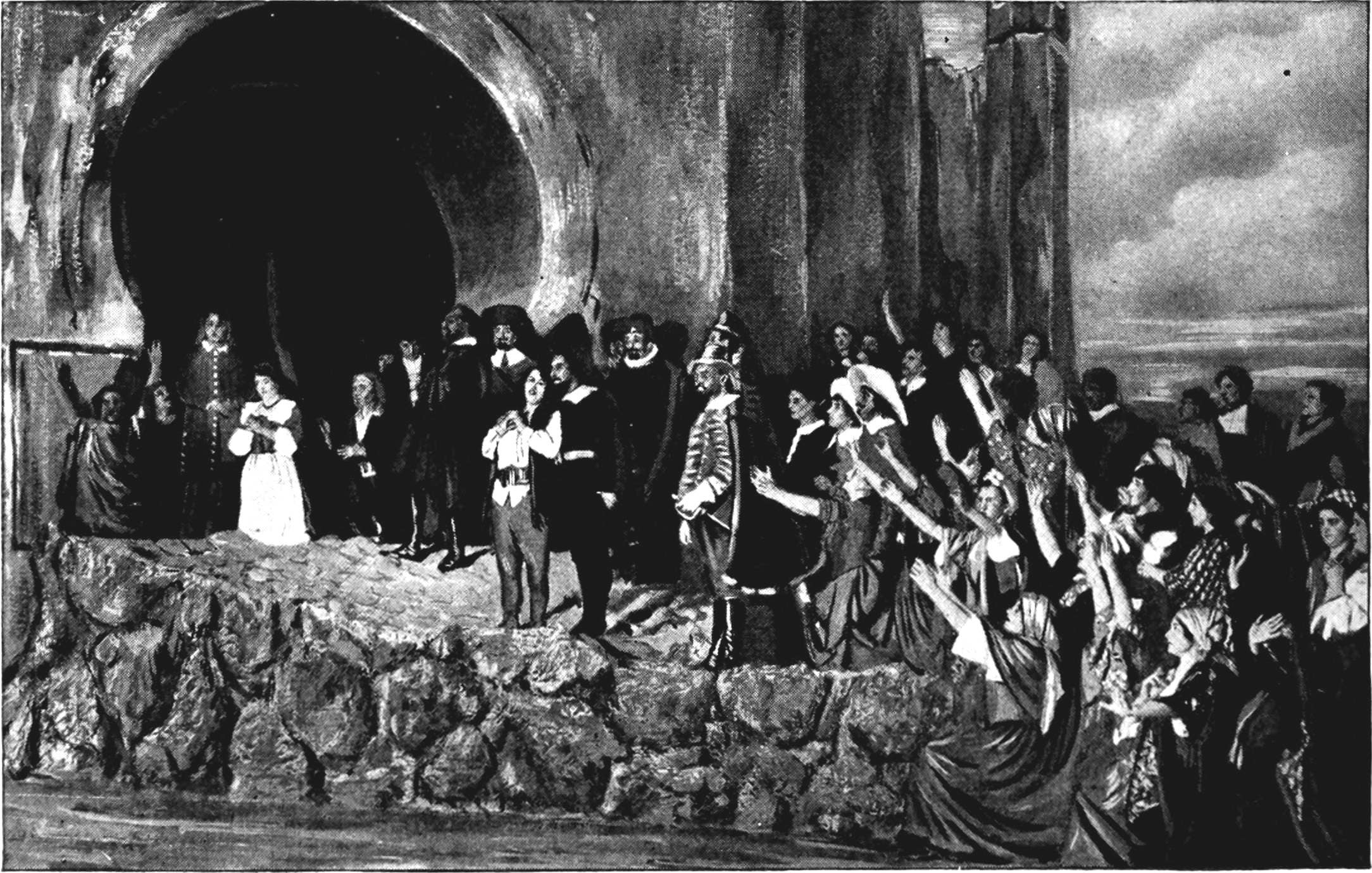 Leonora and Florestan are in the center, with Don Fernando on the side leading rescued prisoners in praise of Leonora’s bravery. They stand on rocky ground near water somewhere along the base of the prison. 