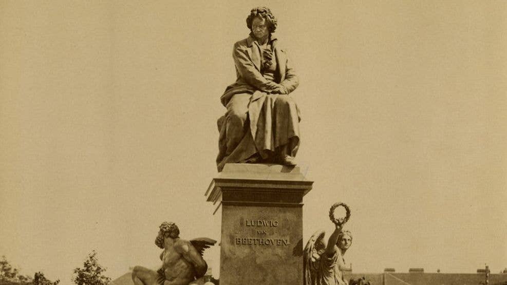 A statue of Beethoven. On his right is Prometheus, on his left is Nike, the goddess of victory. Small putti are at Beethoven’s feet.