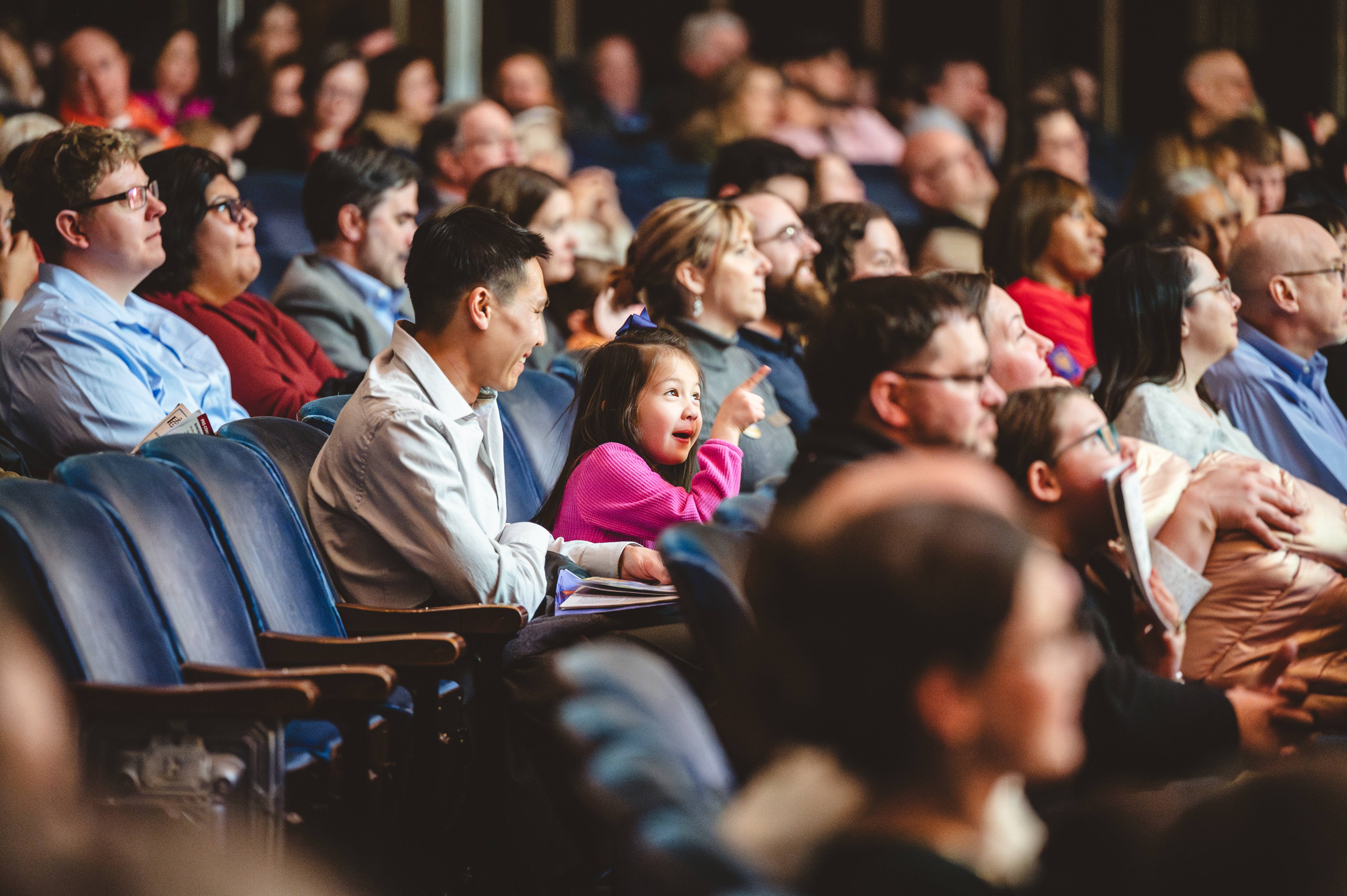 Family concert, with image focus on young child smiling with her father. 