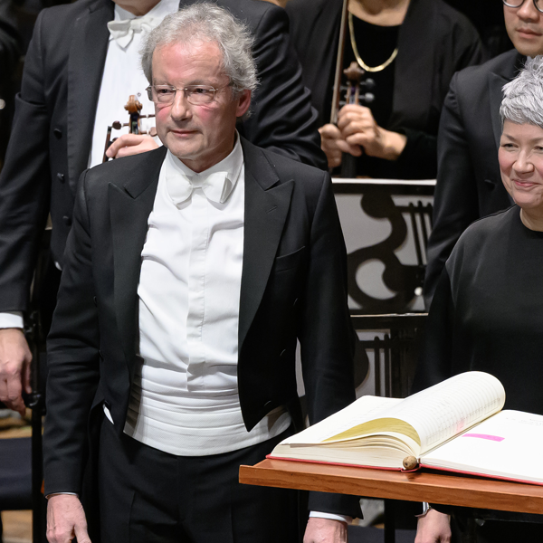 A man in a tuxedo and a woman in black smile behind a podium