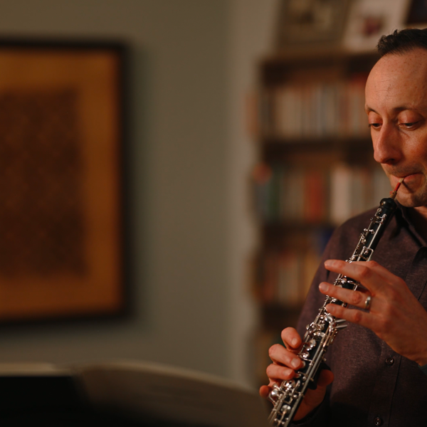 a man in a maroon short plays the oboe