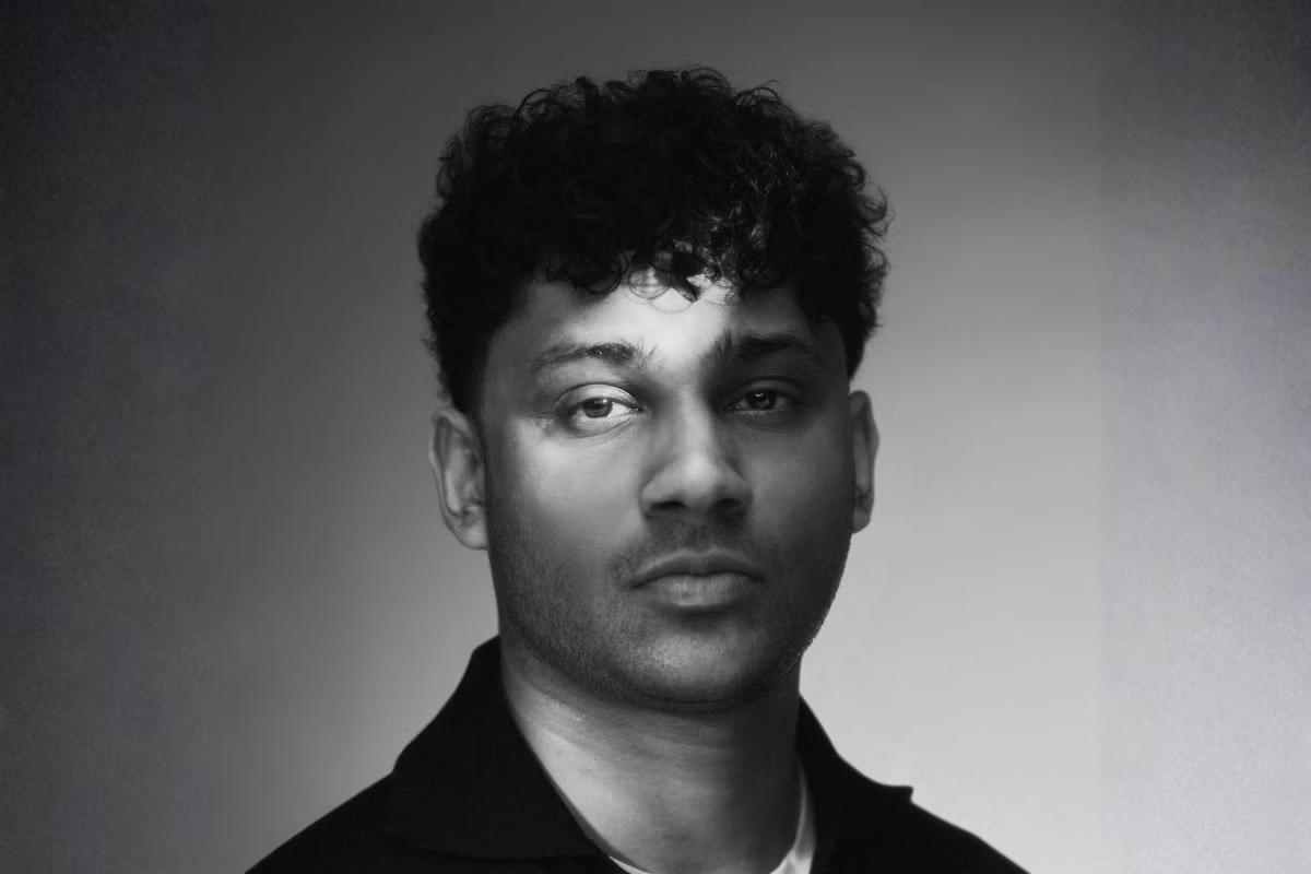 Black-and-white studio headshot of a young man with curly dark hair, facing the camera.