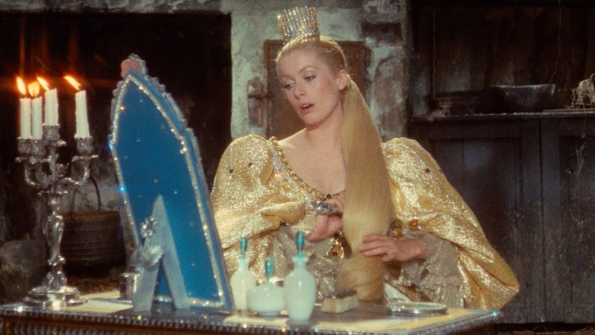 Princess Catherine (played by Catherine Deneuve) in a rustic, dimly lit room, brushing her hair in front of a mirror.