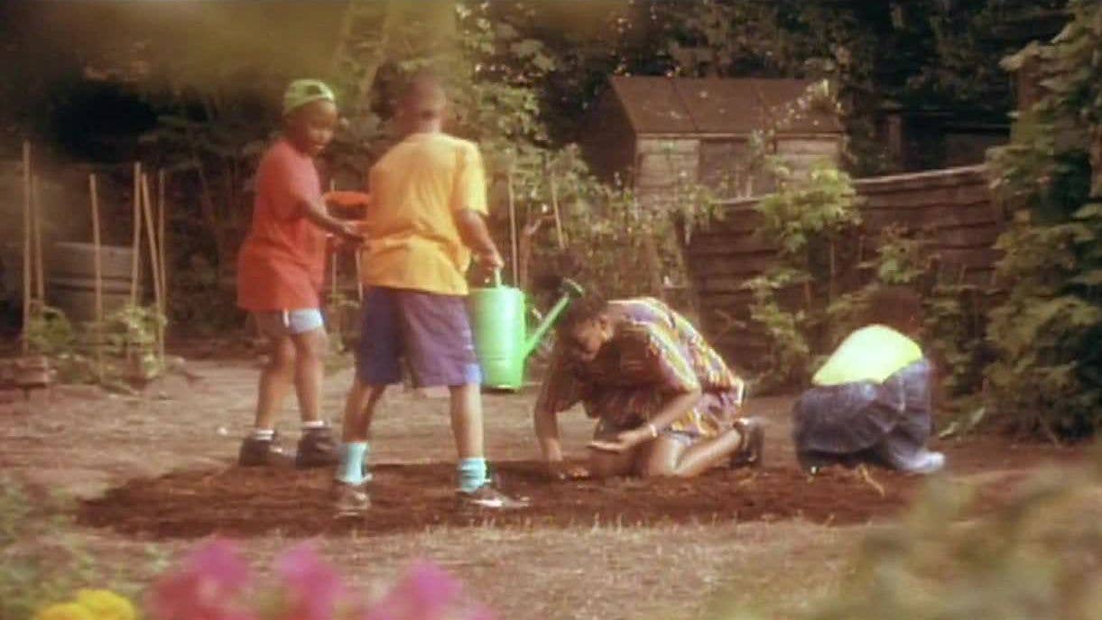 A mother and children planting seeds in the garden