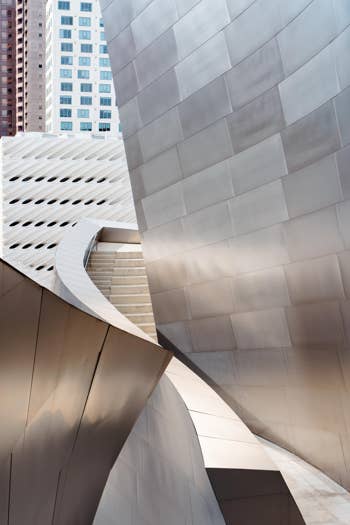 Curving concrete facade and white stairway in a modern building courtyard between high-rise apartments