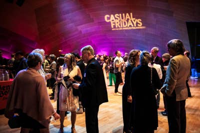 Crowd mingles at a music venue under purple lighting at “Casual Fridays” Los Angeles Philharmonic event.