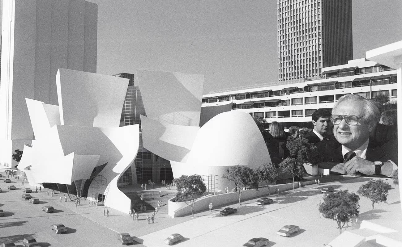 Black-and-white city scene with modern building sculpture, trees, cars, and man smiling in foreground.