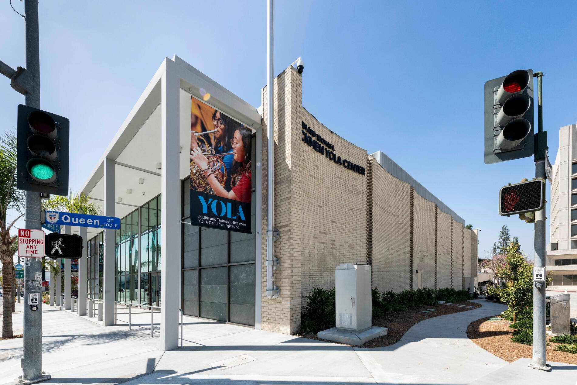 Exterior of the Beckmen YOLA Center at Inglewood with traffic lights and banners under a blue sky