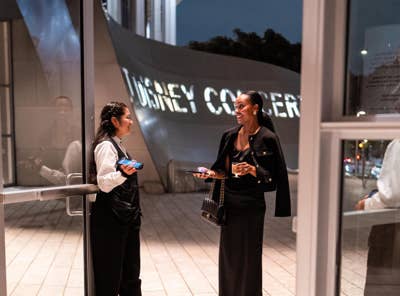 A concert hall usher welcomes in audience member at the Grand Ave entrance.