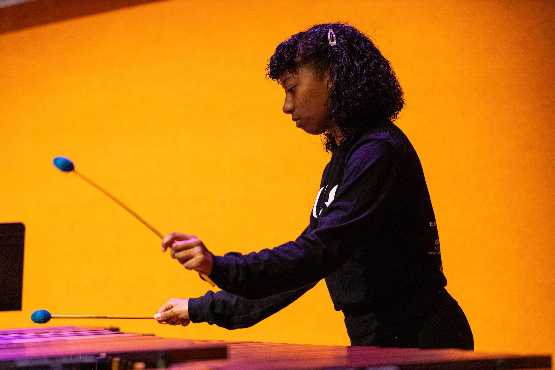 Person with curly hair playing xylophone