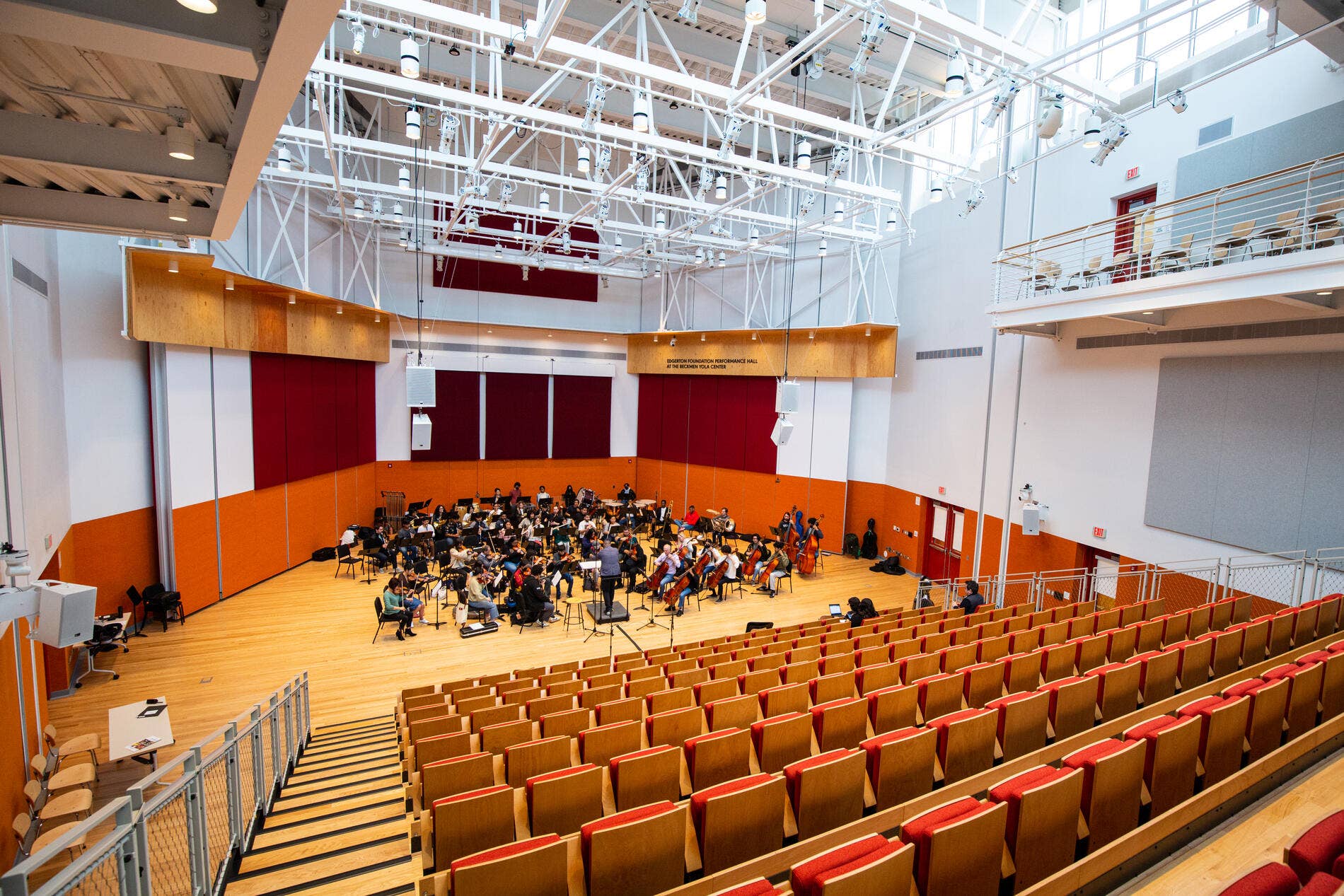 Empty audience seats in the Edgerton Performance Hall with YOLA students practicing on stage.