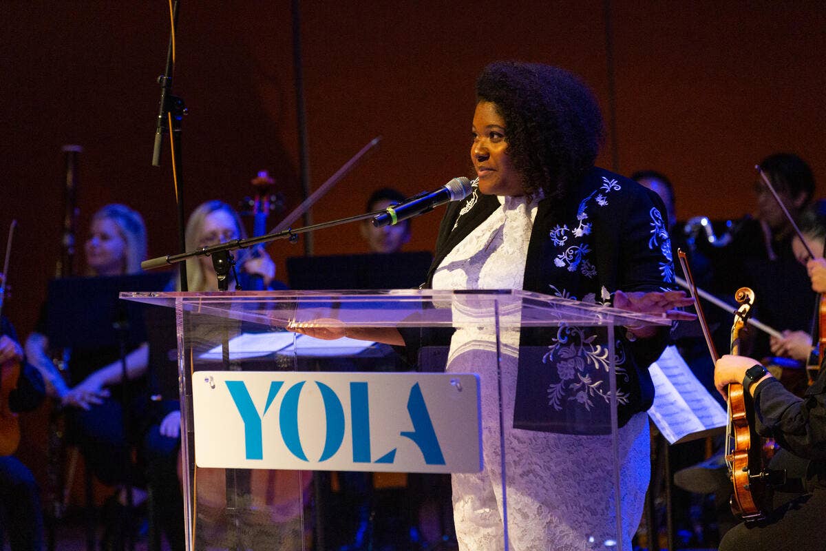Camille Delaney-McNeil speaking at a YOLA event while standing at a YOLA branded podium.