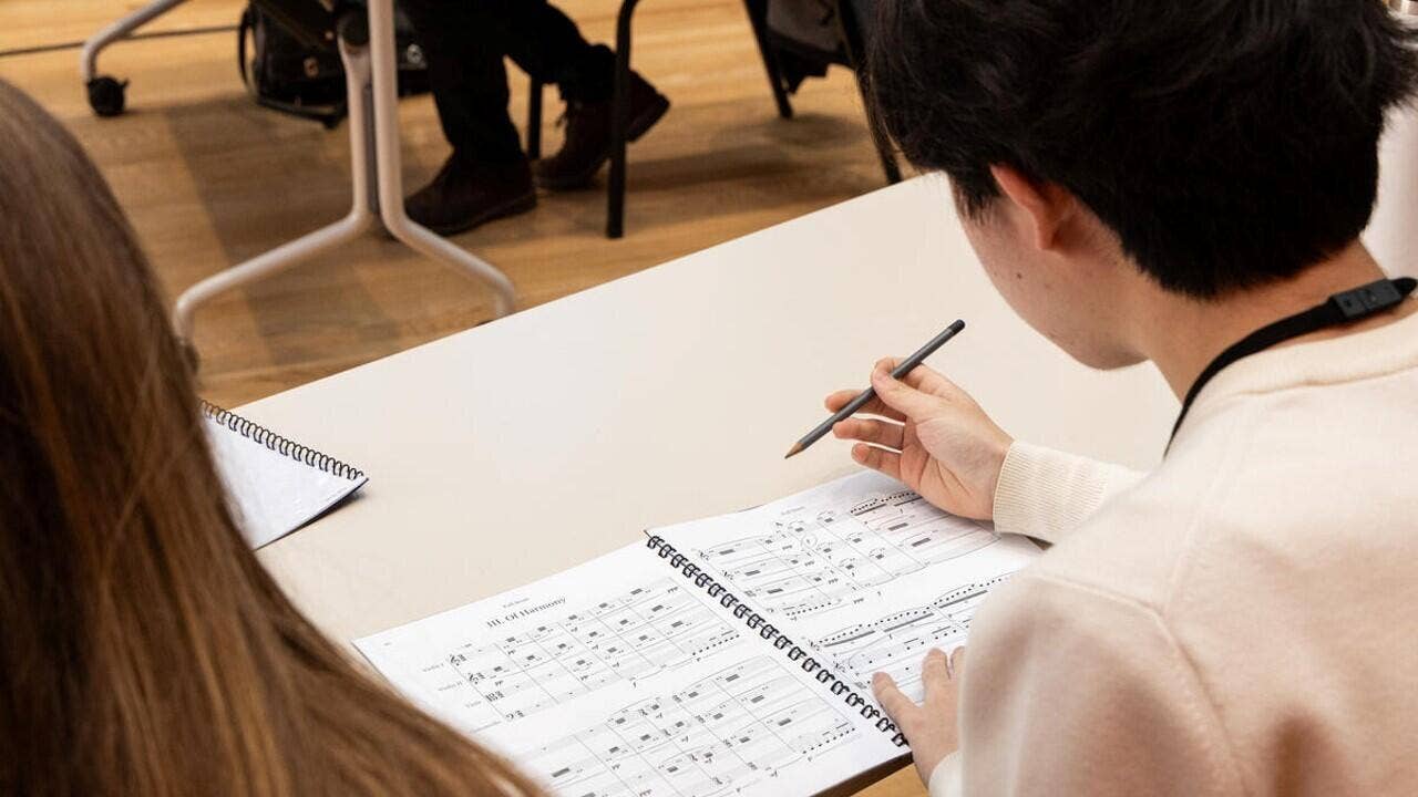 A YOLA student holds a pencil while studying a score during the Composer Fellowship Program.