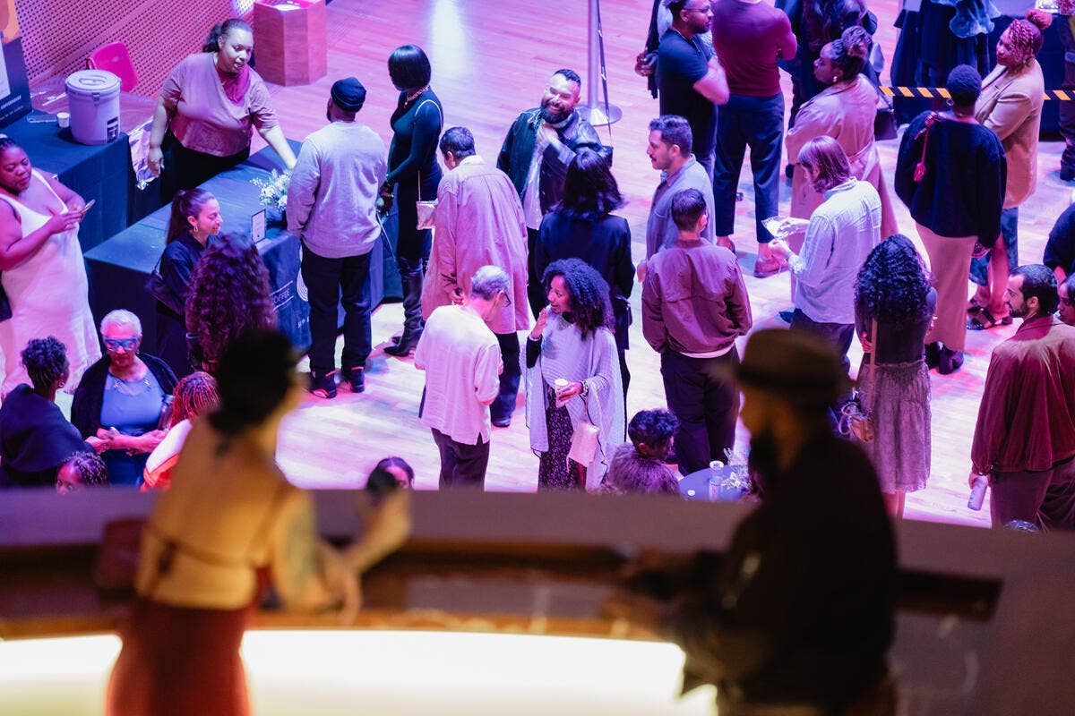 Concert attendees mingling under purple lighting, holding name tags and drinks.
