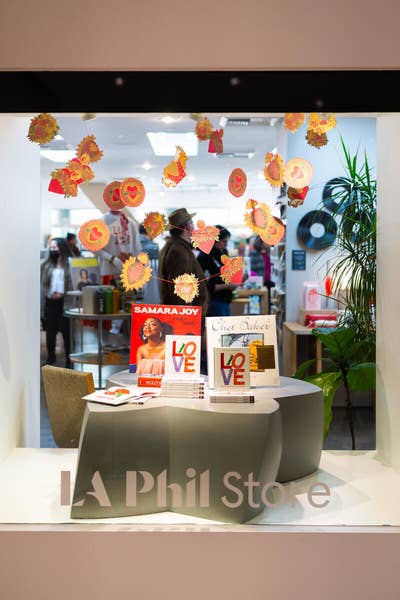 Shop window display with LOVE signs, books, and autumn leaf decorations outside La Phil Store.
