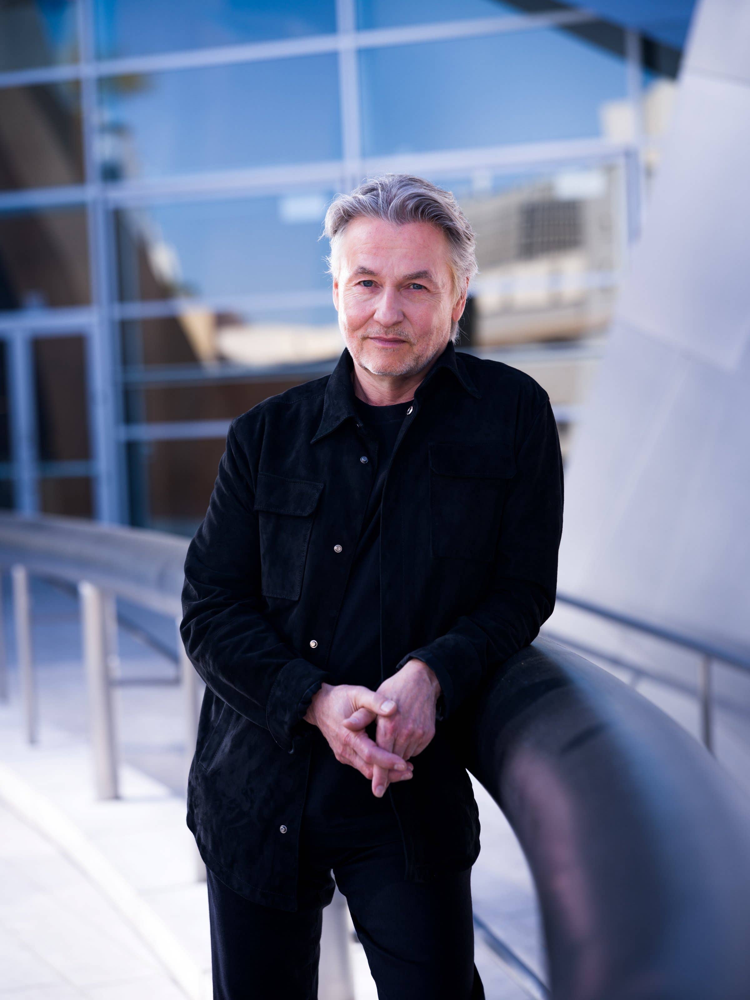 Esa Pekka Salonen leaning on railing in black jacket headshot