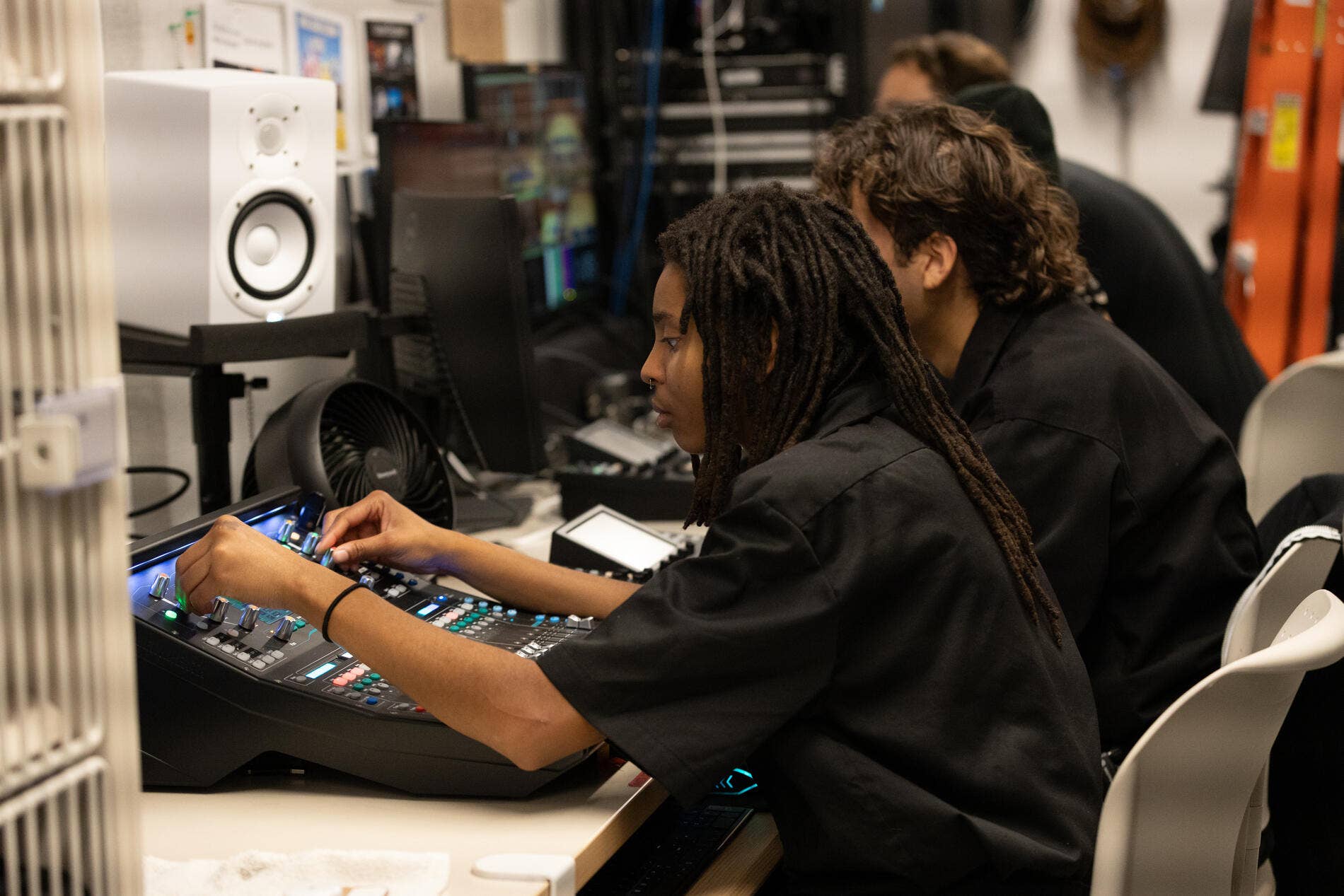 A Workforce Development Program stagehand mixes audio backstage for a live stream.