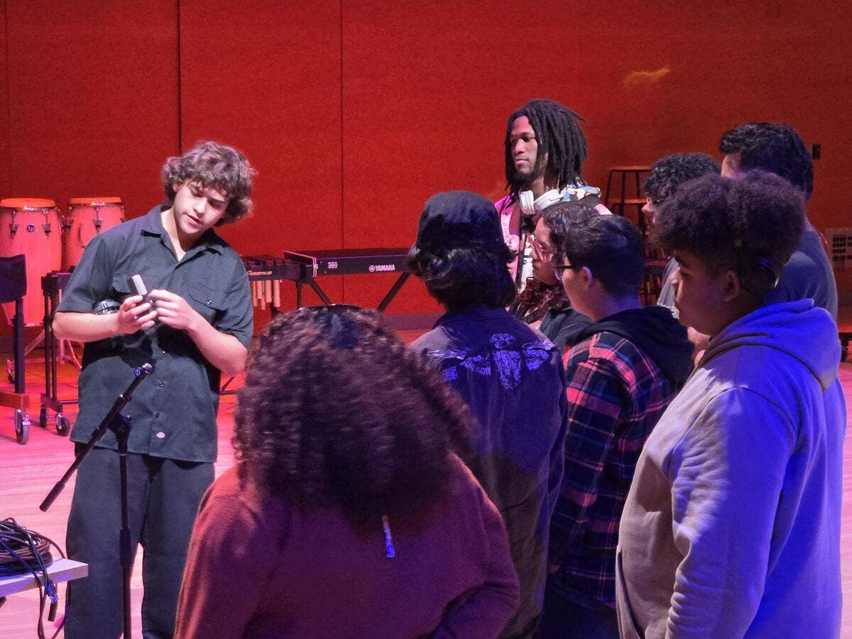 IATSE Workforce Development students learn the details of a microphone during a class on stage. 